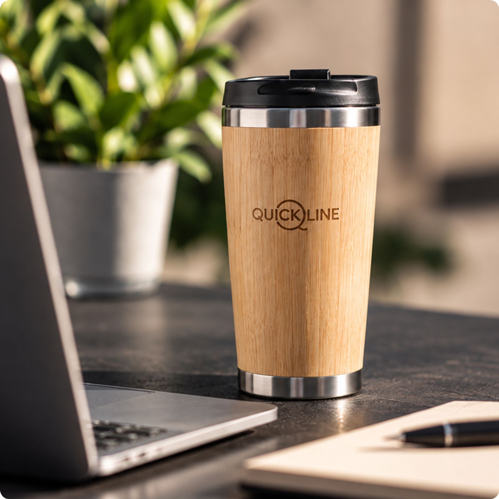 Mug isotherme en bambou avec le logo Quickline sur le bureau