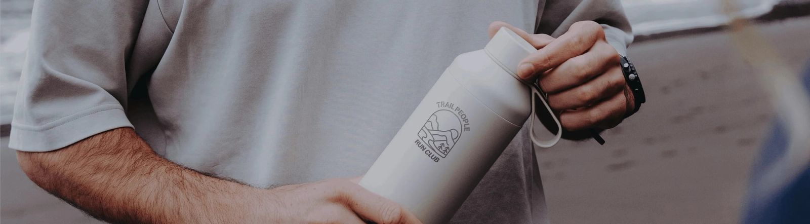 Un jeune homme tient entre ses mains une gourde blanche imprimée avec un logo.