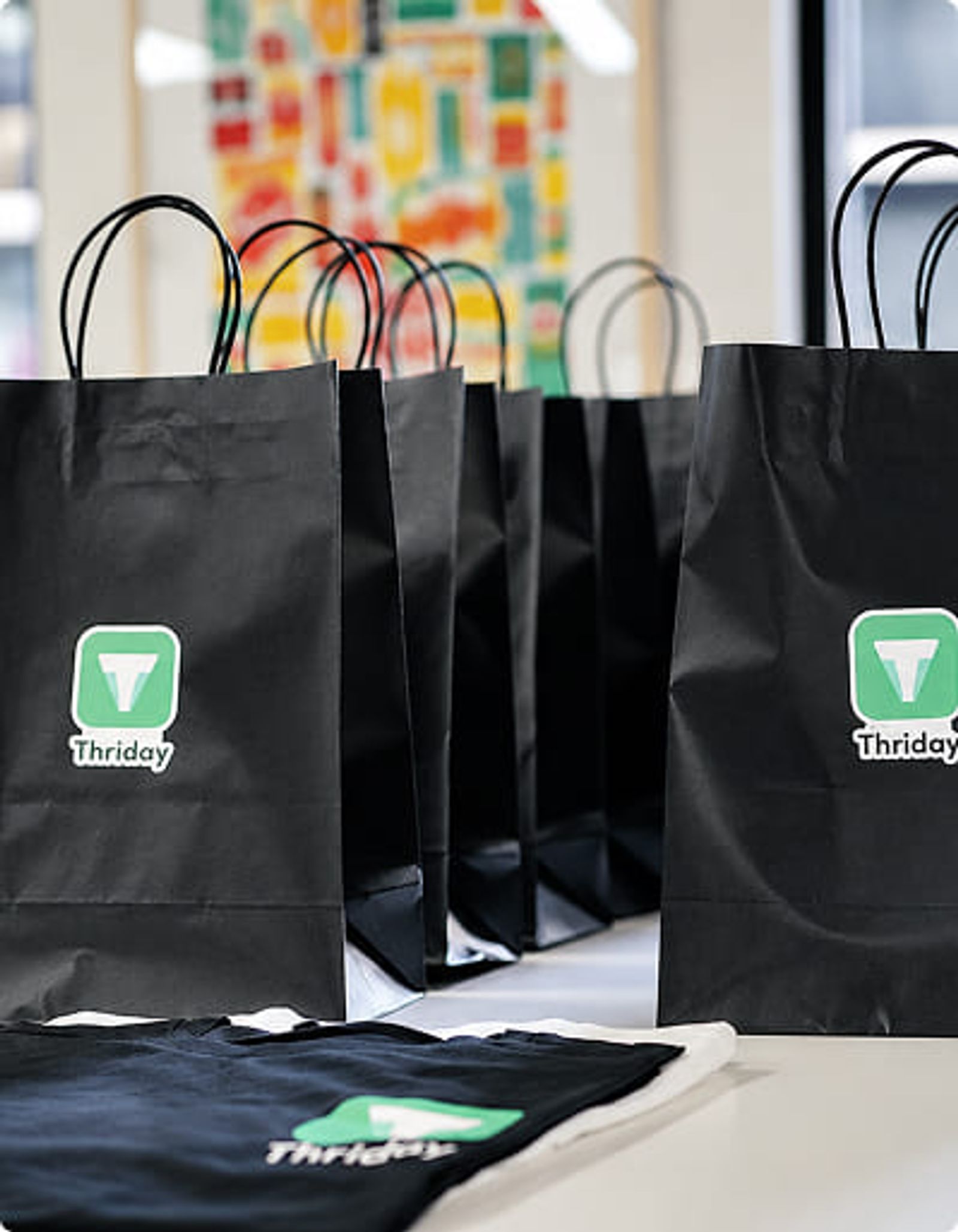 Schwarze Event-Giveaway-Taschen mit individuell bedrucktem Logo und gebrandetem T-Shirt, vorbereitet für eine Firmenveranstaltung.
