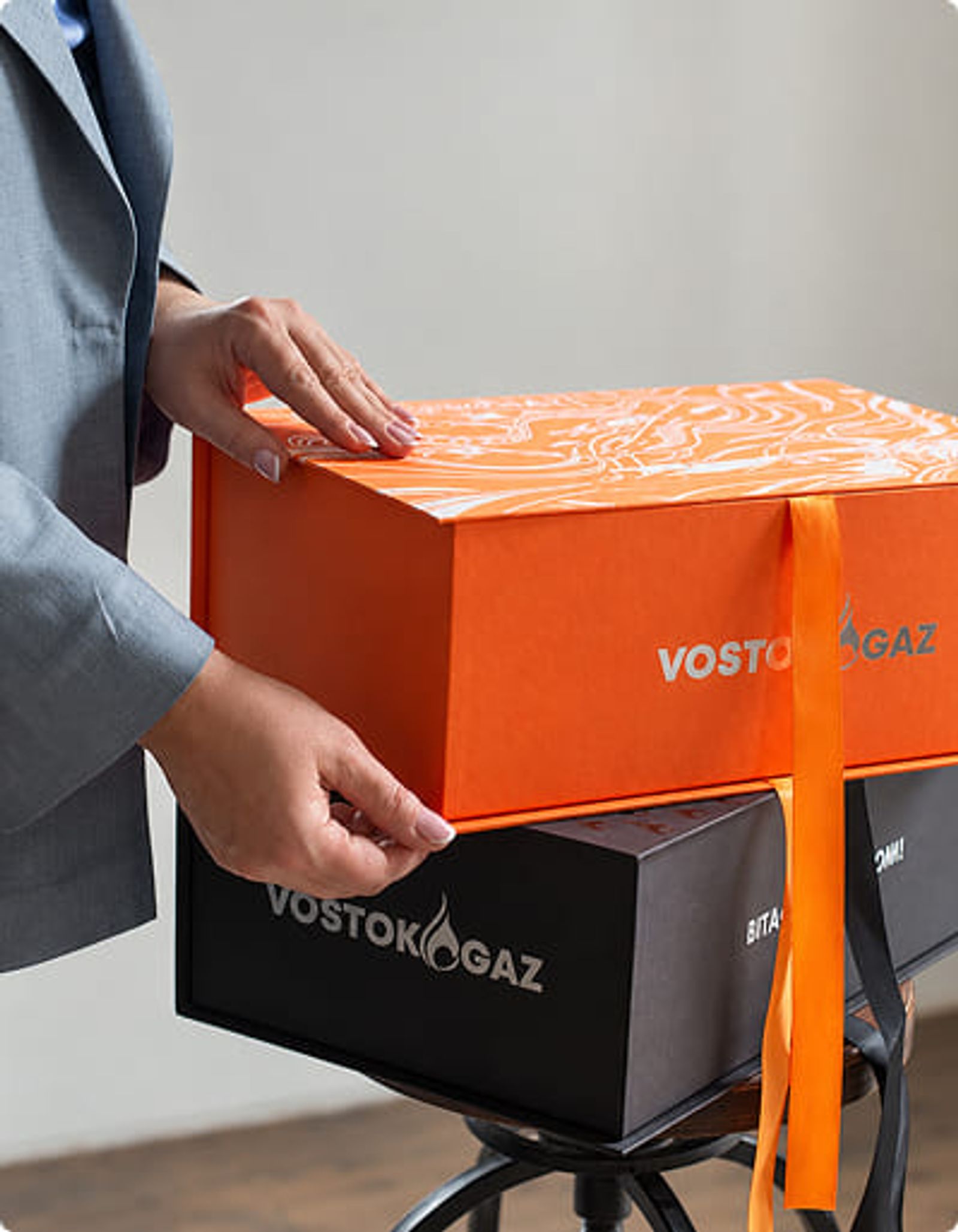 Person mit hochwertigen, individuell gebrandeten Geschenkboxen als Mitarbeitergeschenk.