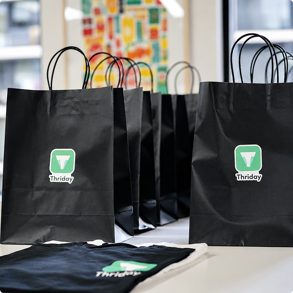 Gebrandete schwarze Papiertaschen und T-Shirts als individuell gestaltete Giveaways für Events und Firmenanlässe.
