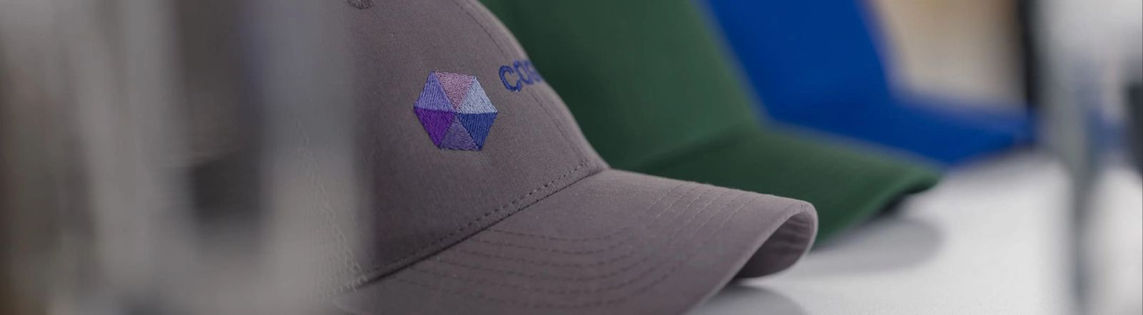 Plusieurs casquettes alignées, brodées avec un logo d’entreprise