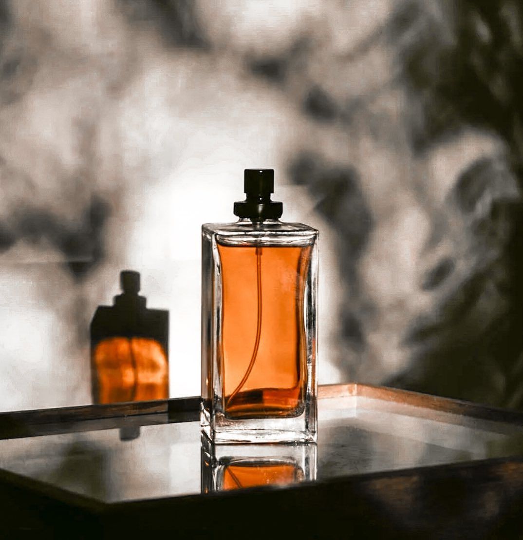 Un flacone di profumo ambrato su un ripiano a specchio