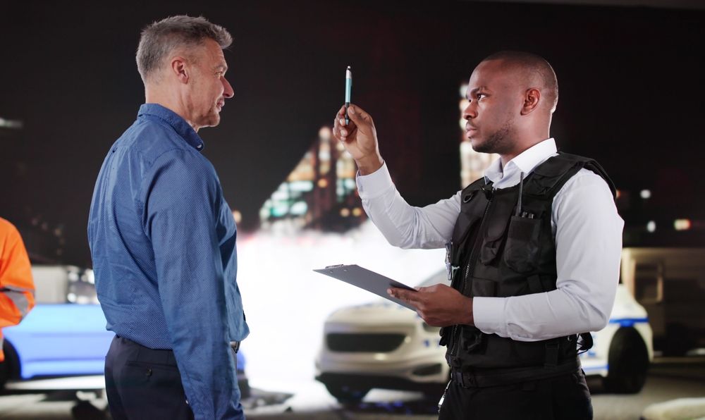 A law enforcement officer performing a horizontal gaze nystagmus (HGN) field sobriety test on a driver during a nighttime traffic stop.