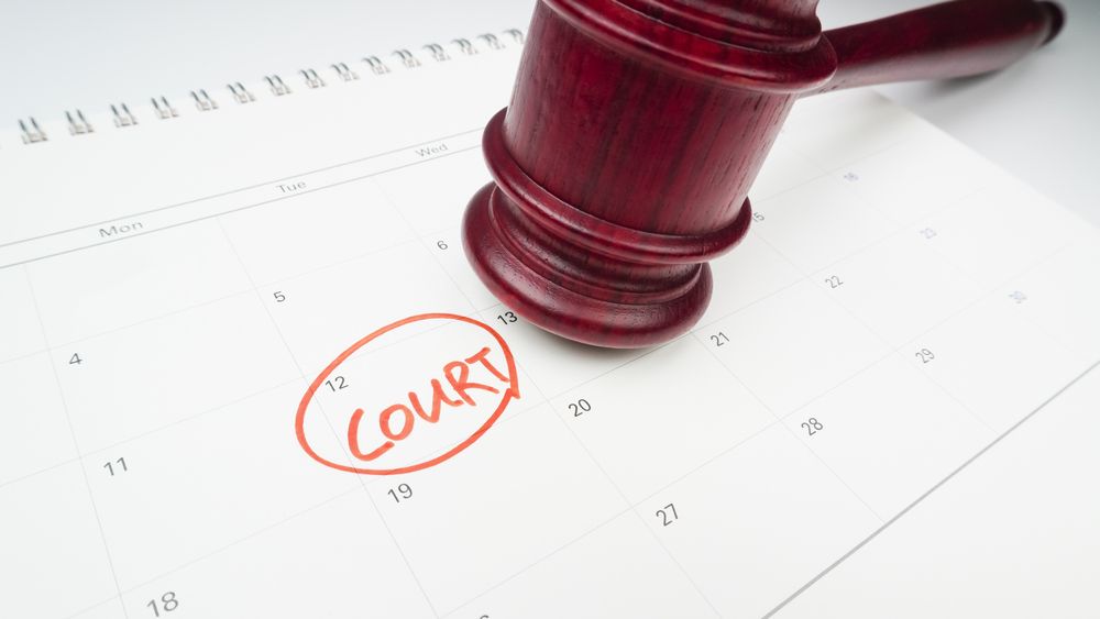 A red wooden gavel resting on a desk calendar with a red circle around the word 'COURT'.