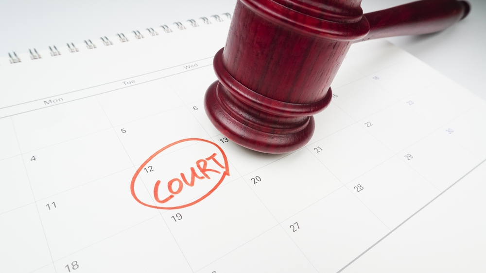 Image A red wooden gavel resting on a desk calendar with a red circle around the word 'COURT'.