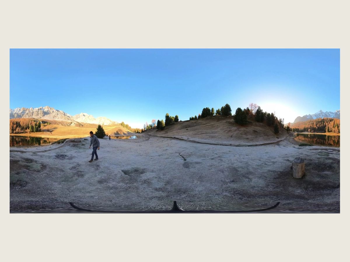 Image panoramique à 360° du lac Miroir : un homme marche sur la rive givrée, une souche est posée à droite