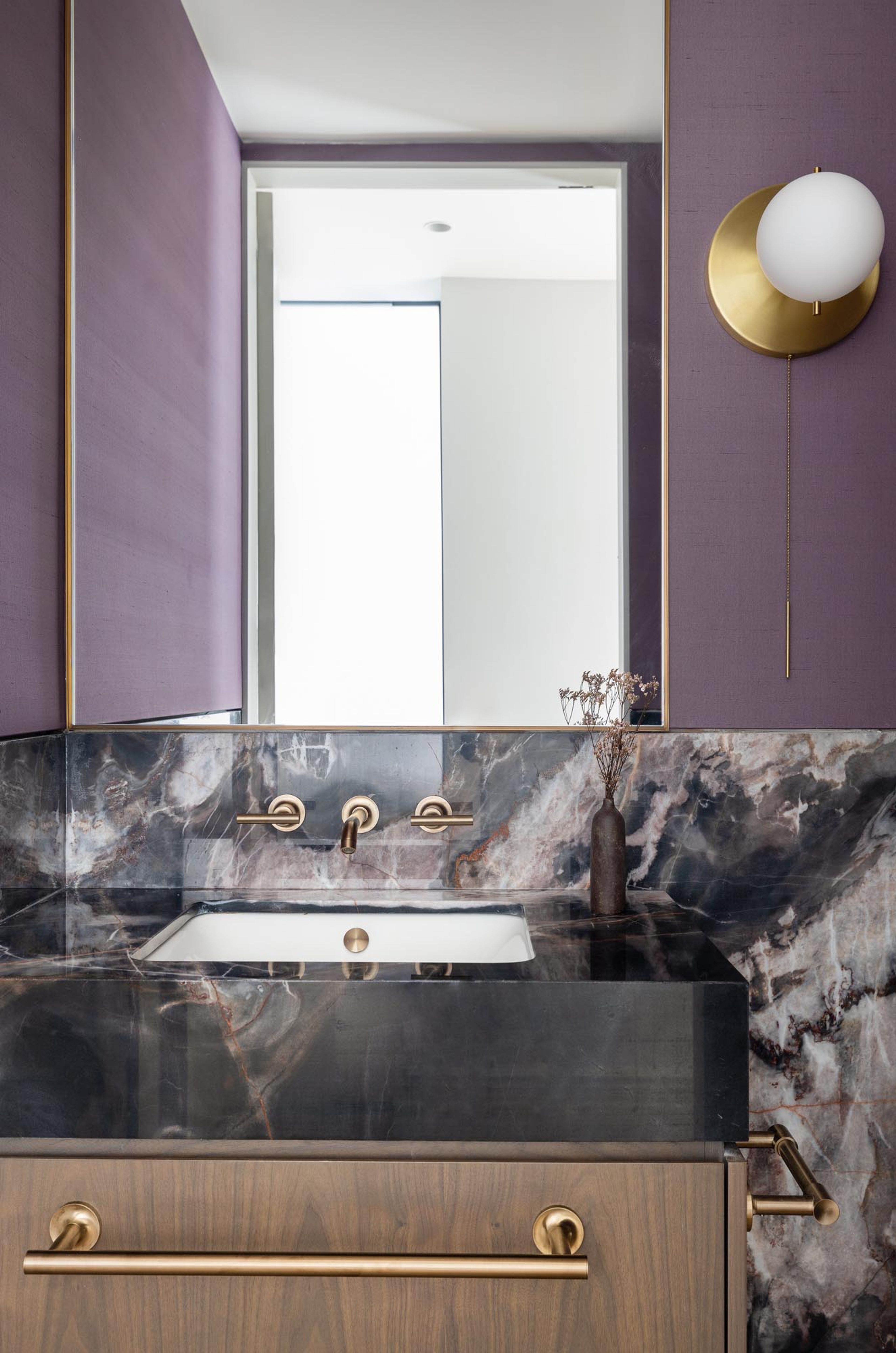 Bathroom with marble counter, purple walls, and fluted glass doors in Riverside Residence.