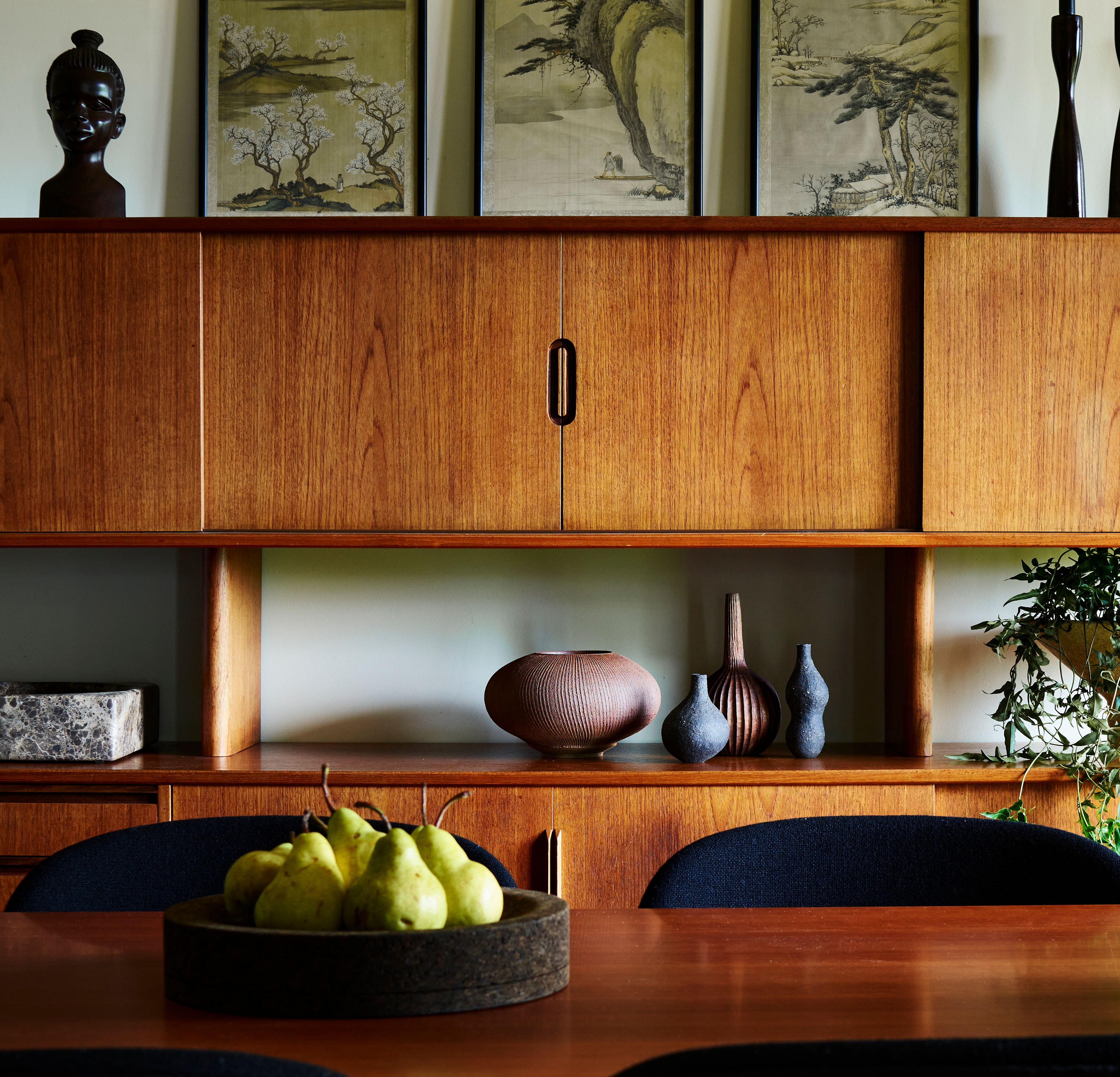 A wooden cabinet with a bowl of fruit on it, adding a touch of nature to the Amherst Residence's dynamic and stylish interior design.