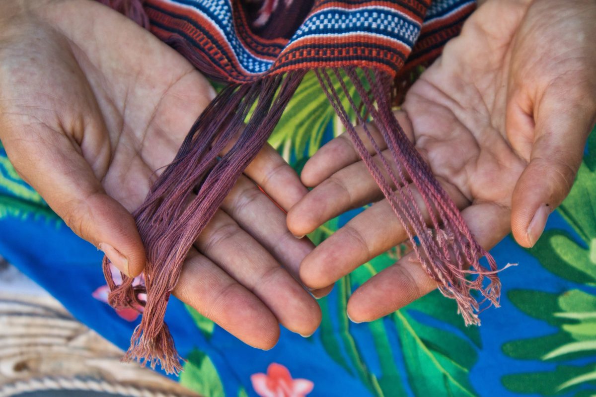 Twisted purple fringe threads held in a weaver’s hands