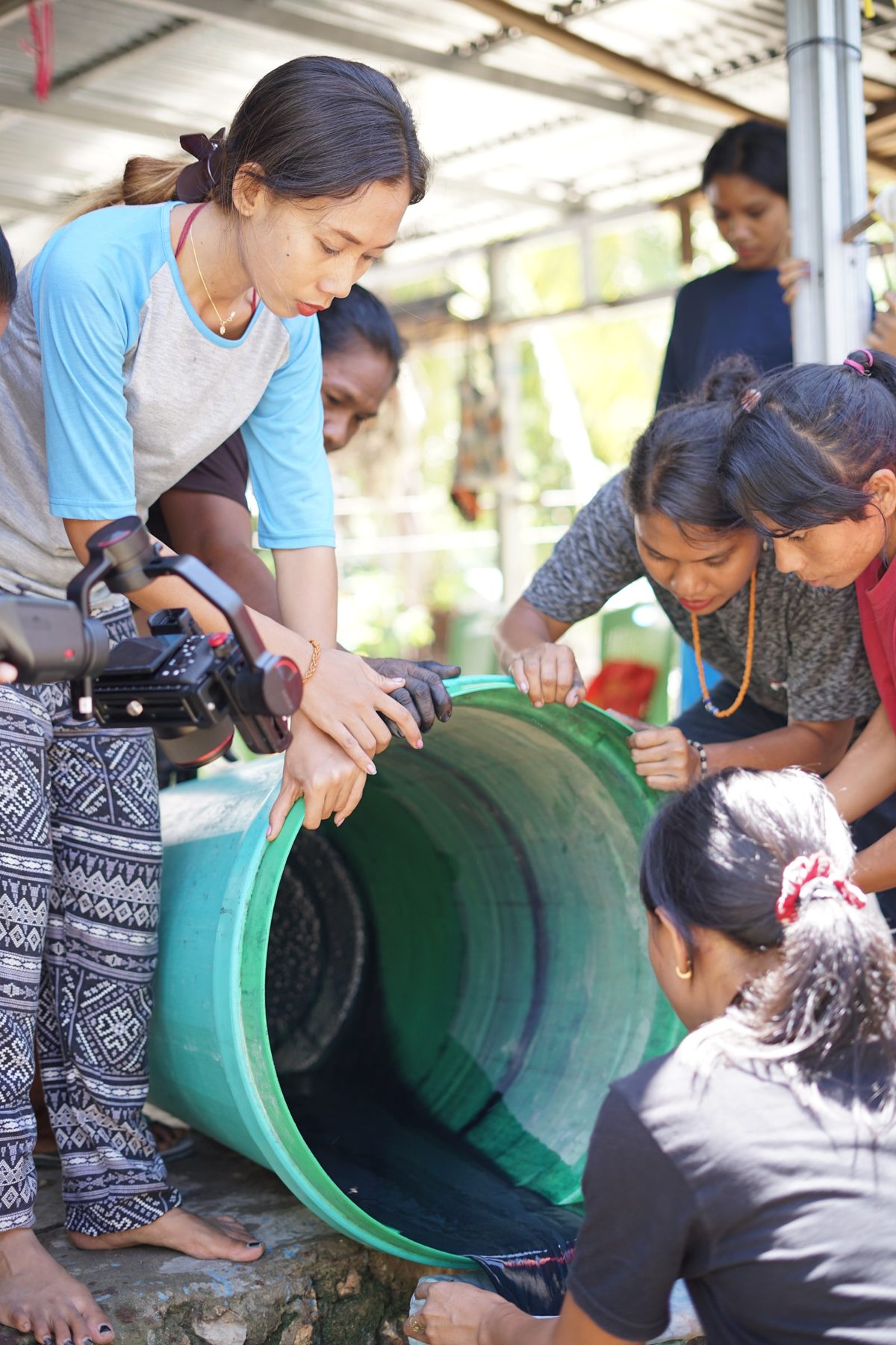 Participants pouring liquid from a green basin during indigo preparation