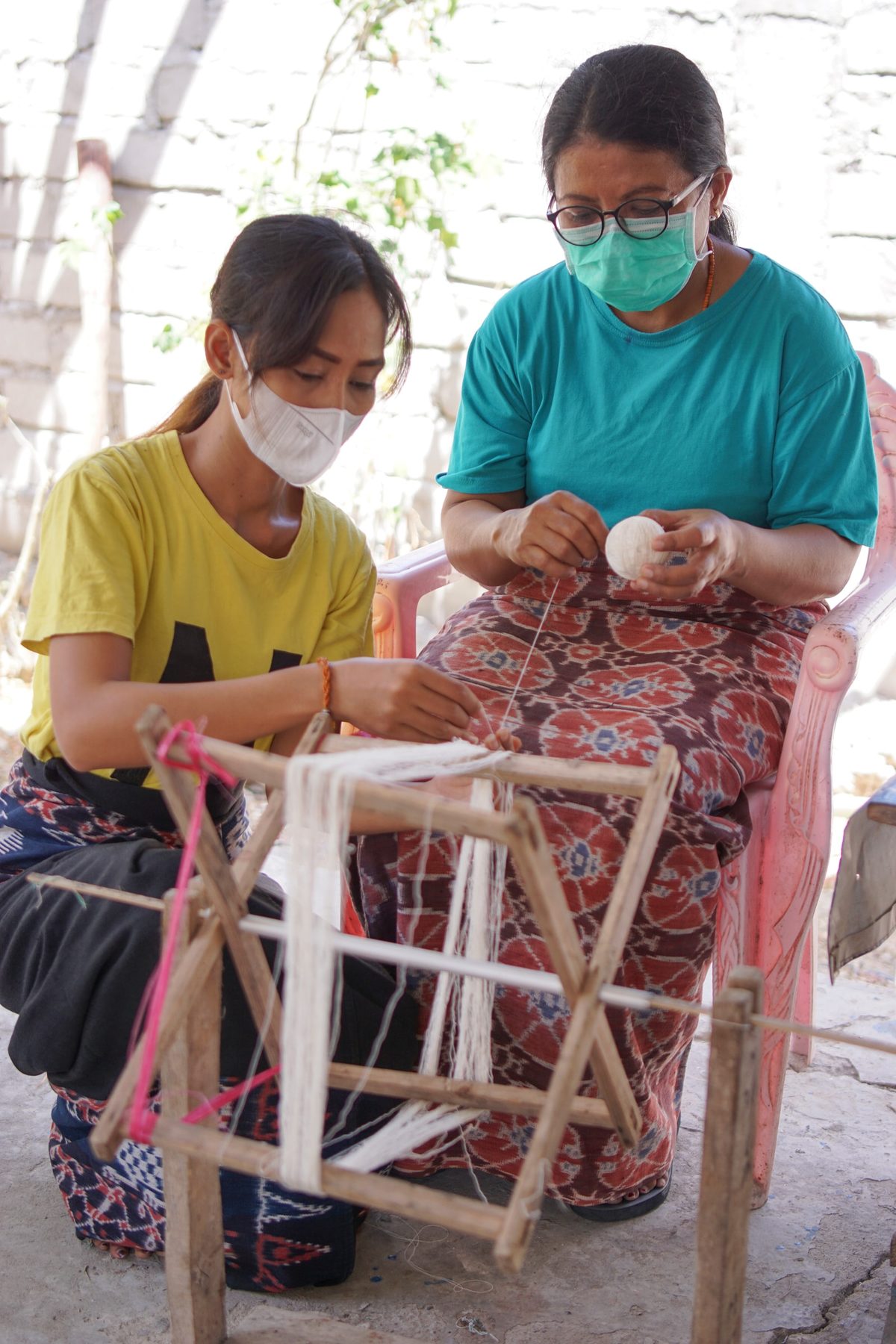 A participant and teacher winding cotton yarn together