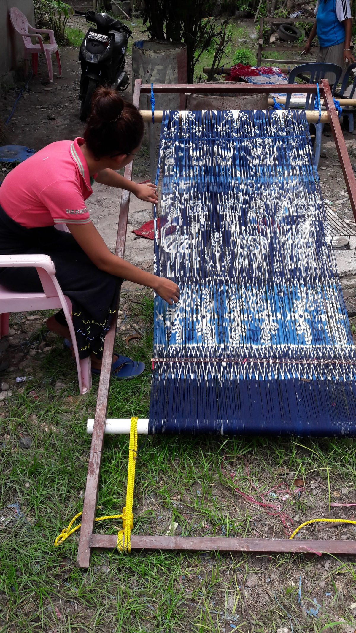 A woman separating indigo warp threads outdoors