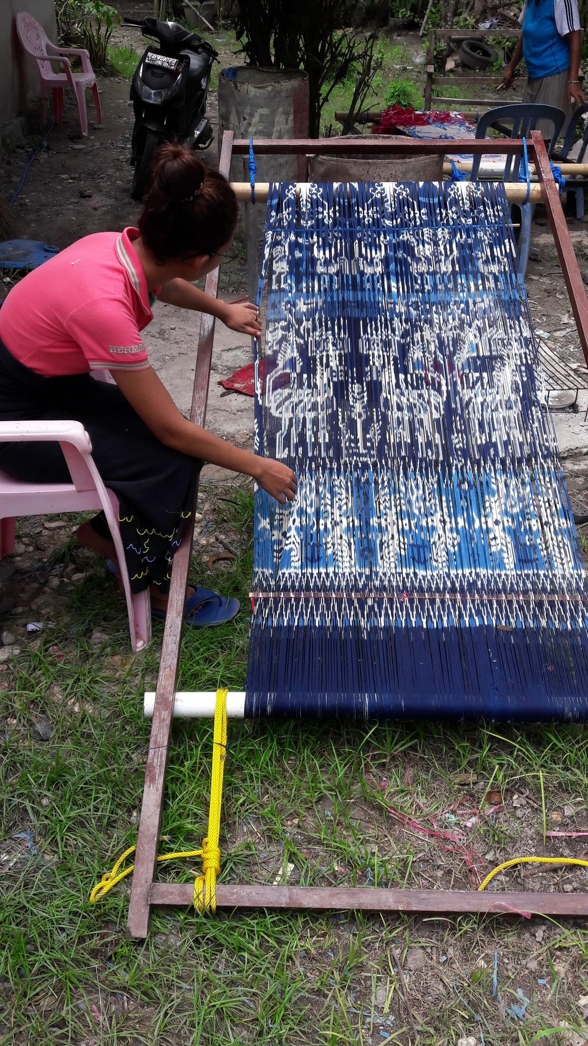 A woman separating indigo warp threads outdoors