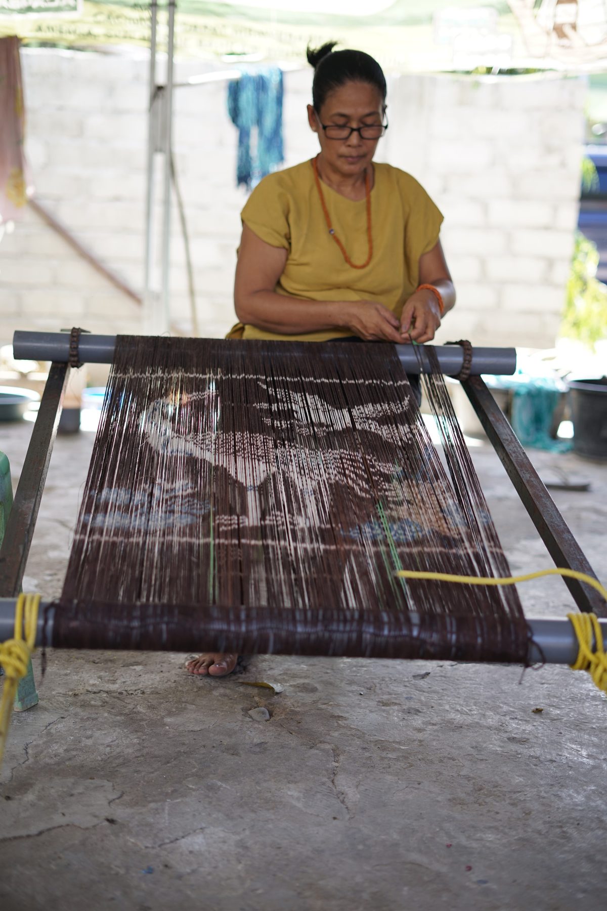 A woman arranging an Ikat motif on a thread frame