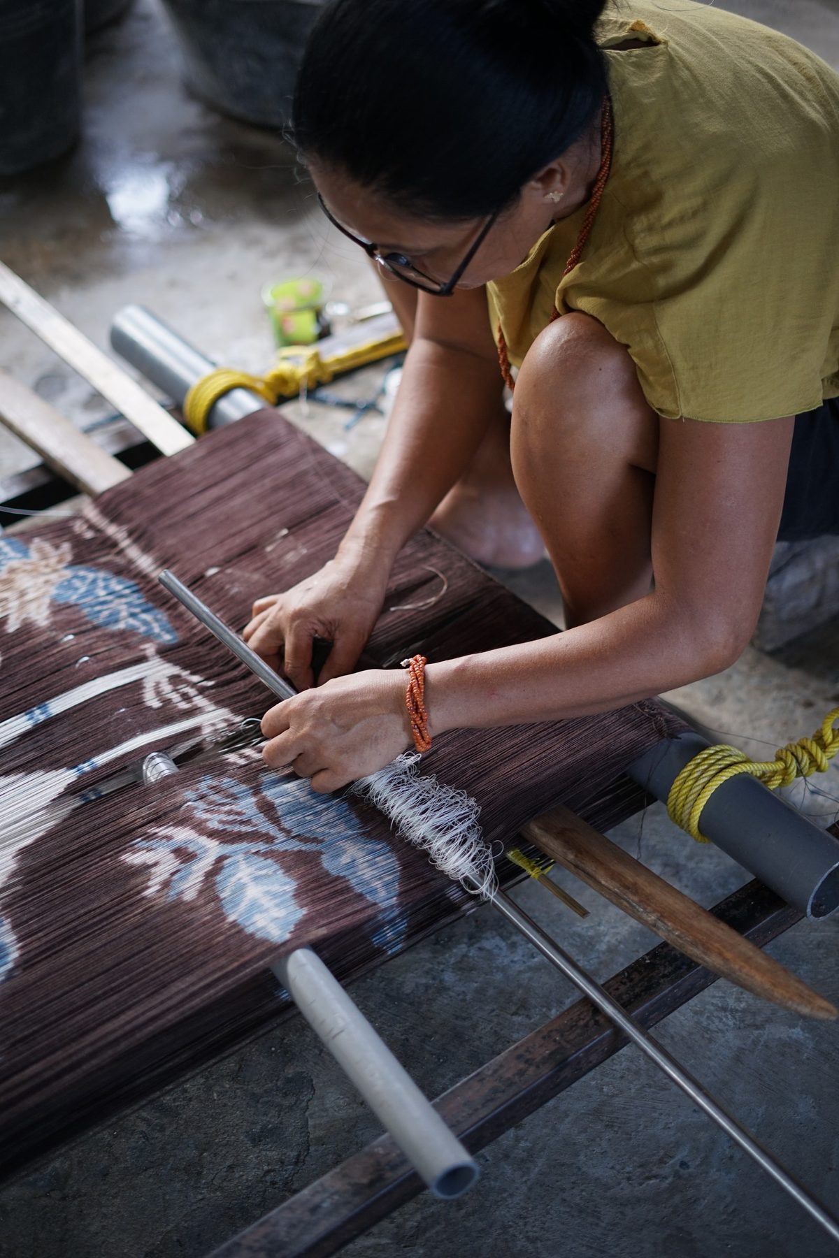 A woman making guide threads over a prepared warp