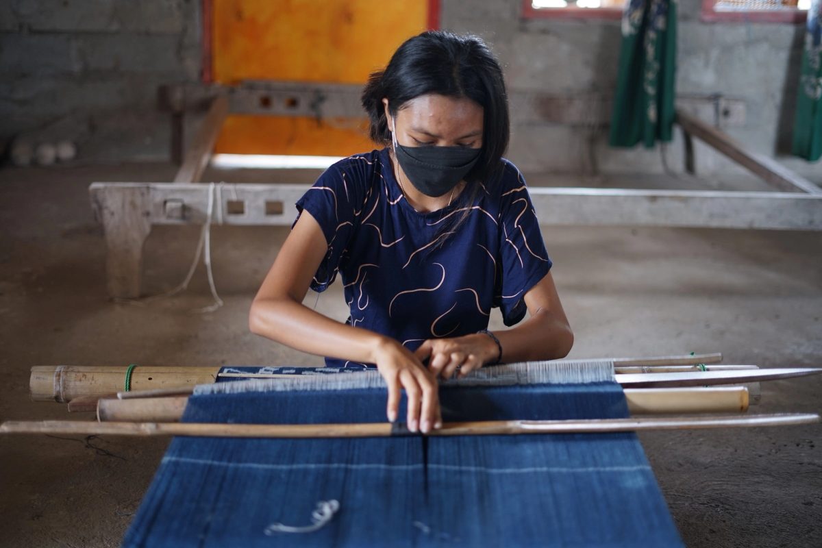 A woman concentrating on her work at an indigo loom