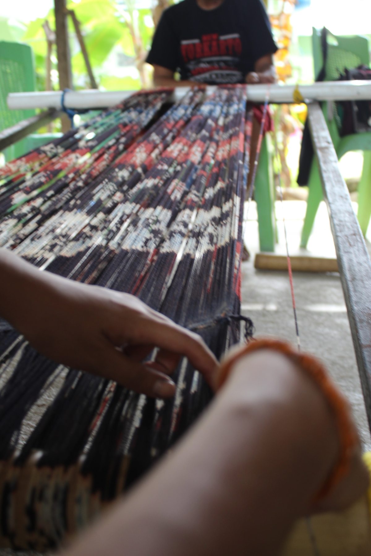 Hands aligning patterned threads across a wooden frame