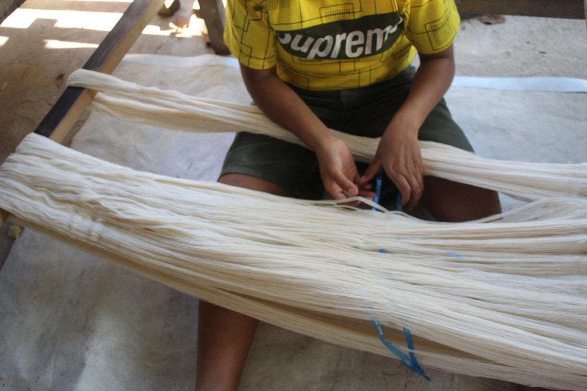 A woman separating white strands across her lap