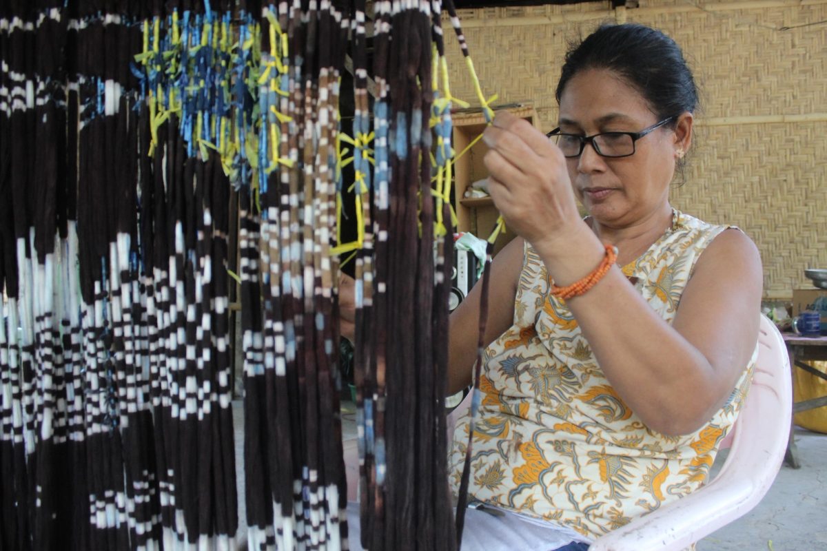 A woman opening the resist ties on patterned yarn