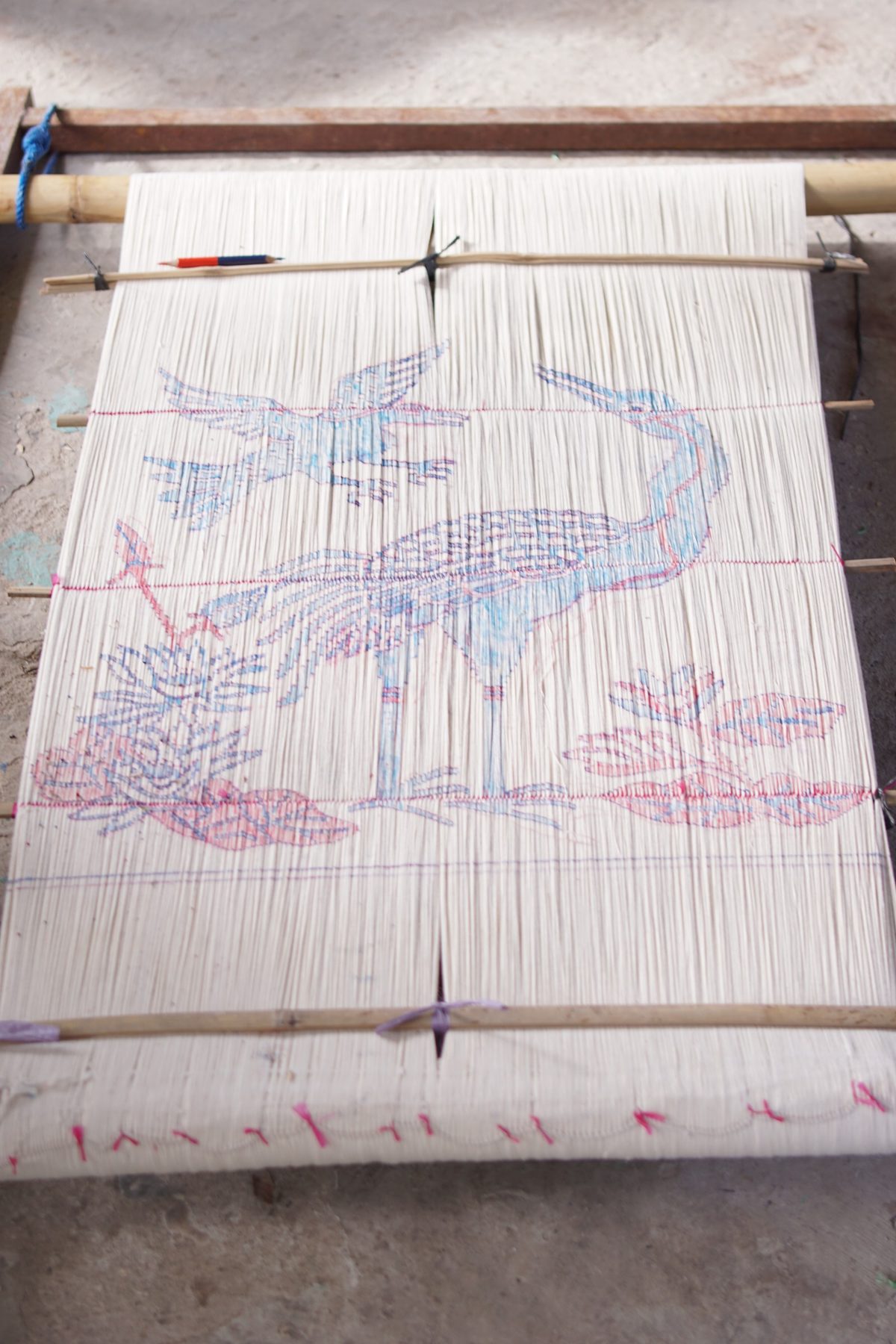 A drawn bird motif on white threads, ready for resist tying