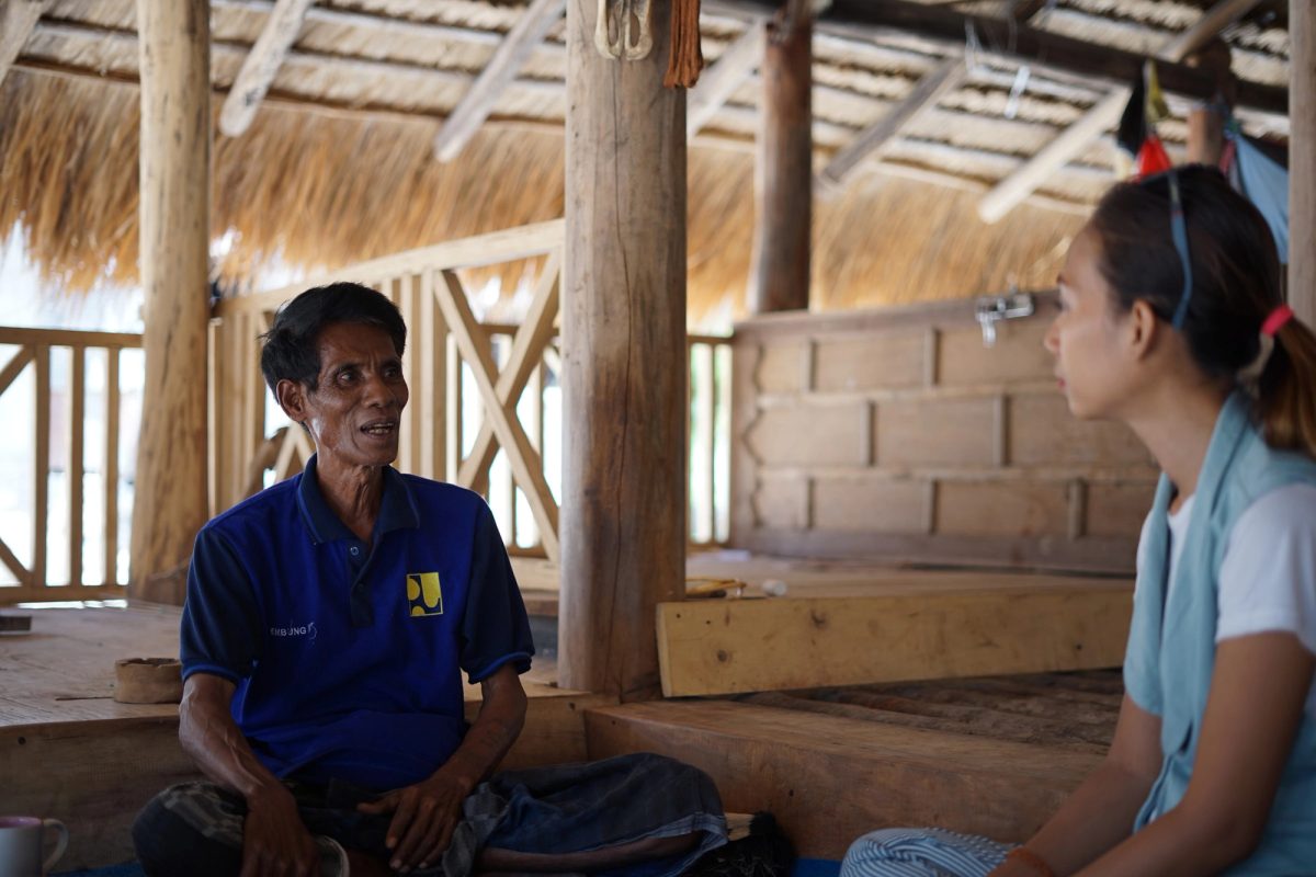 Two people sharing a conversation inside a thatched wooden house