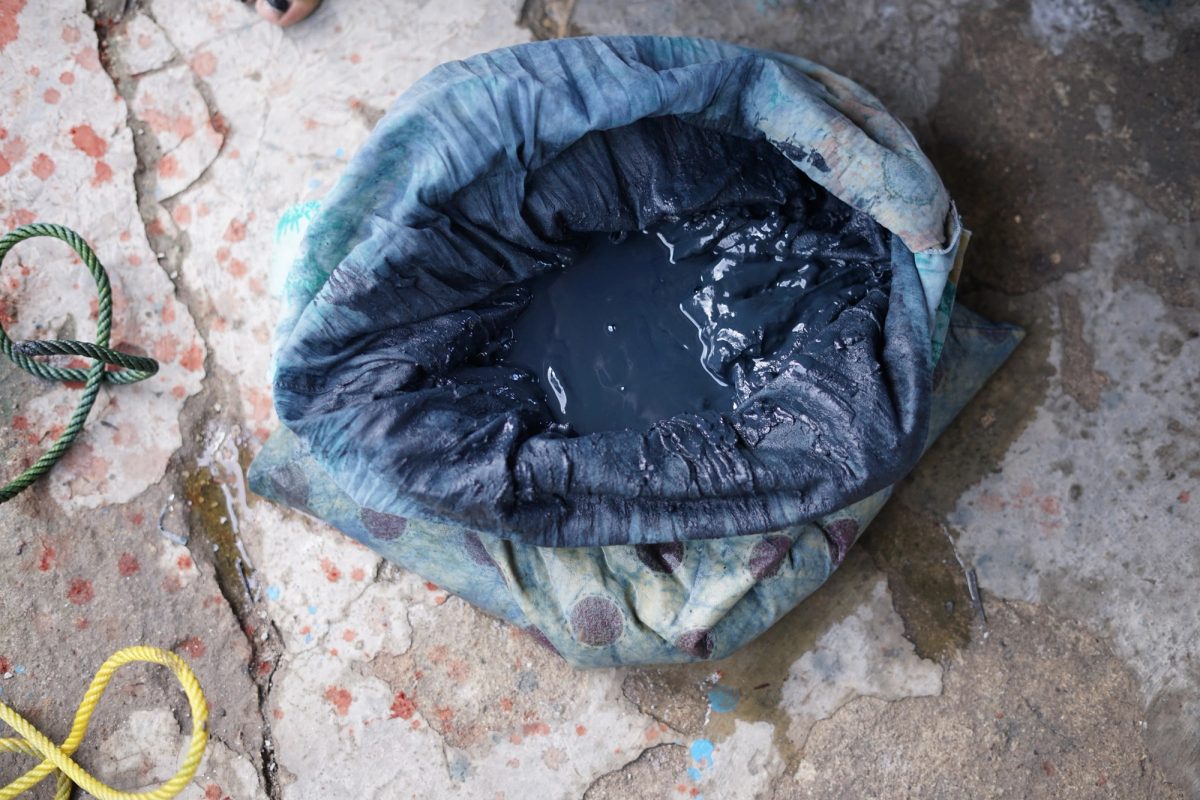 Deep blue yarn soaking in a dark indigo dye vessel
