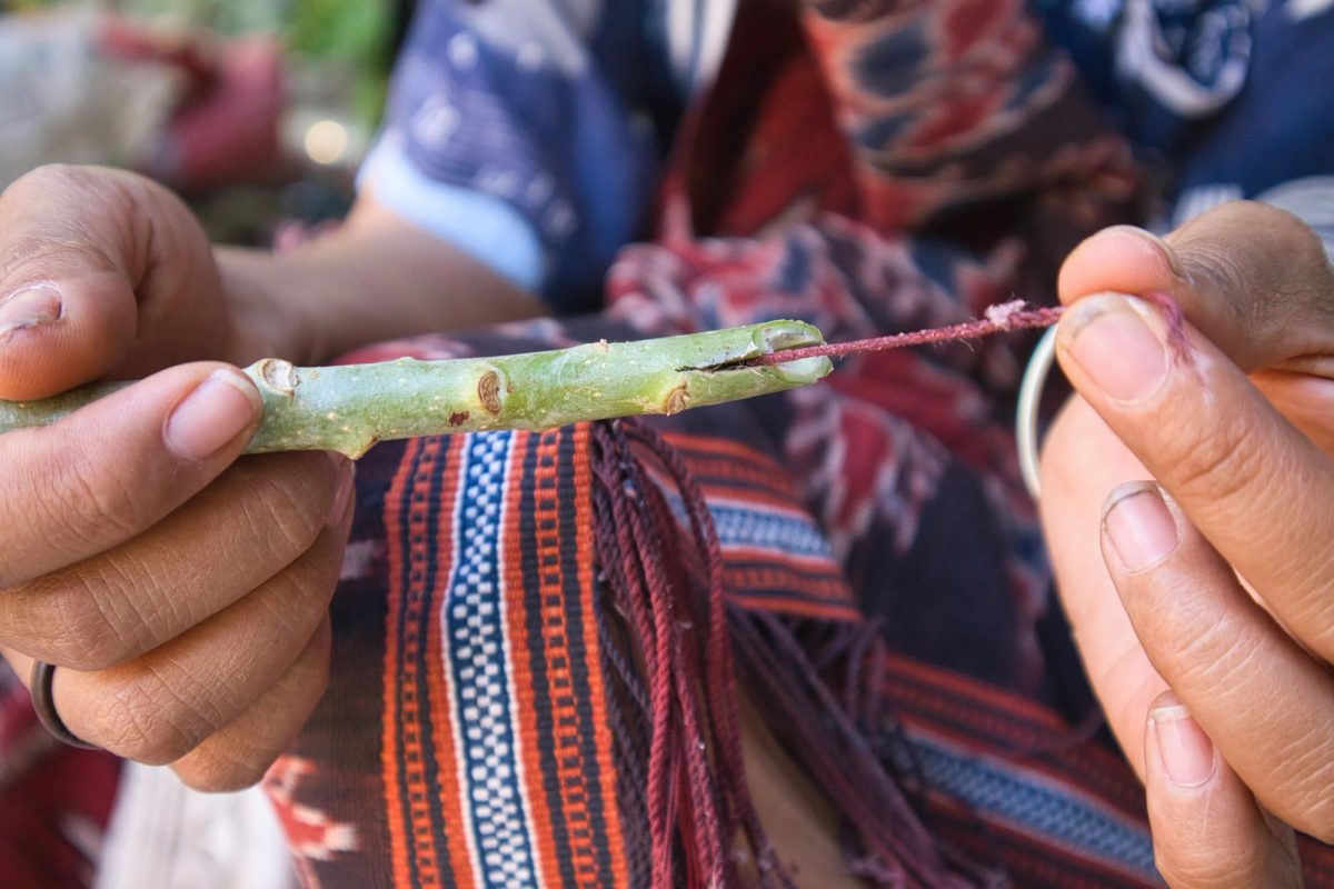 A weaver smoothing twisted fringe with a small green stem