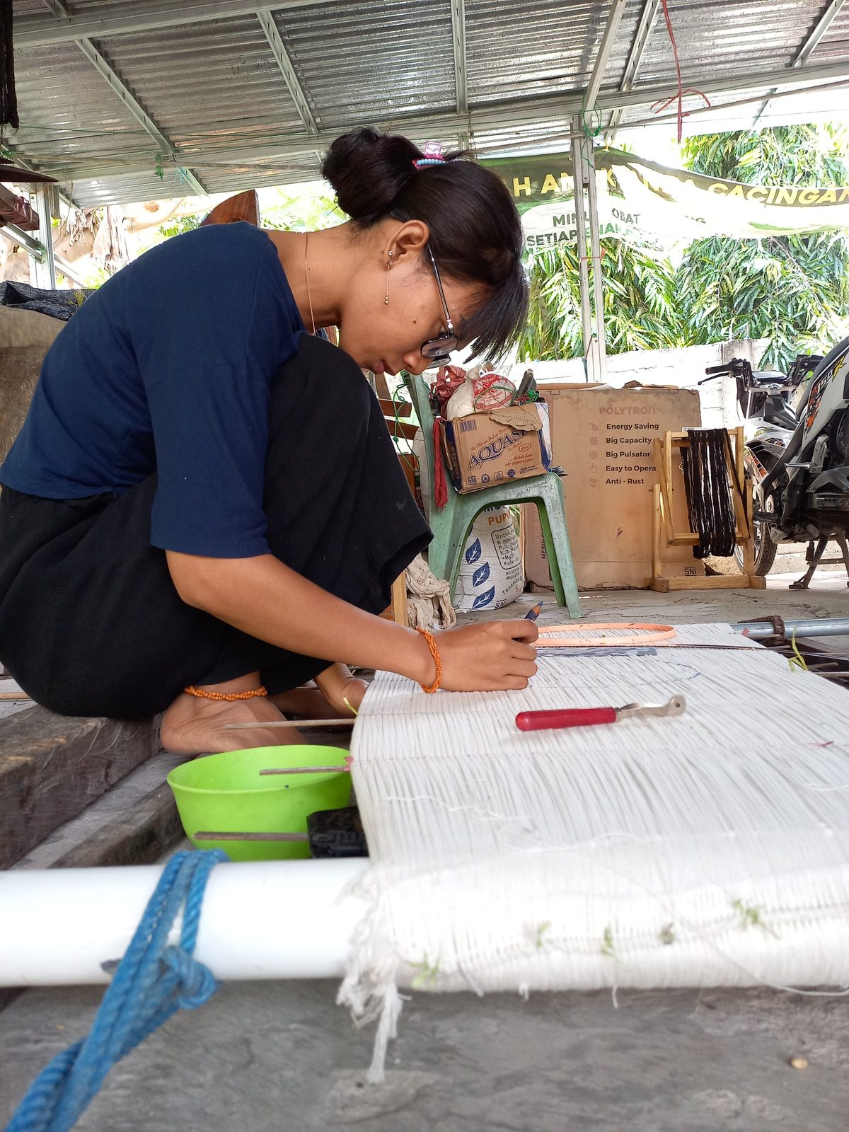 A woman drawing an Ikat motif on a thread frame