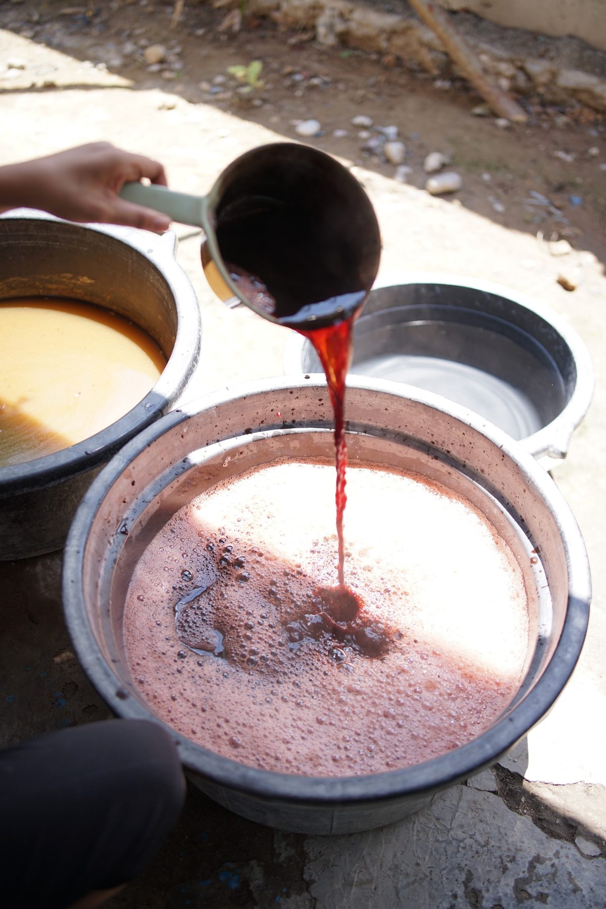 Red dye being poured into a large metal basin