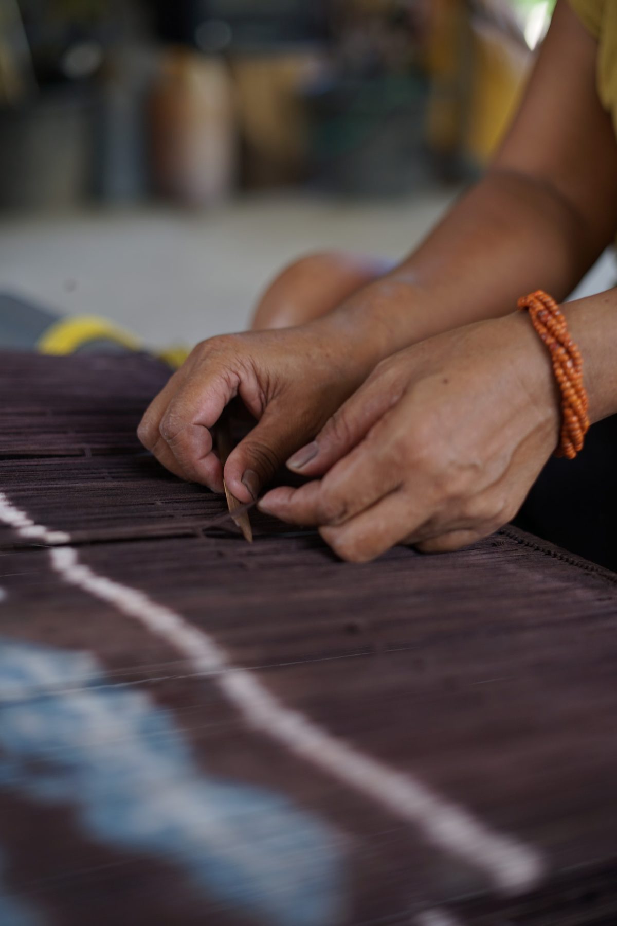 Fingers checking individual strands in the warp