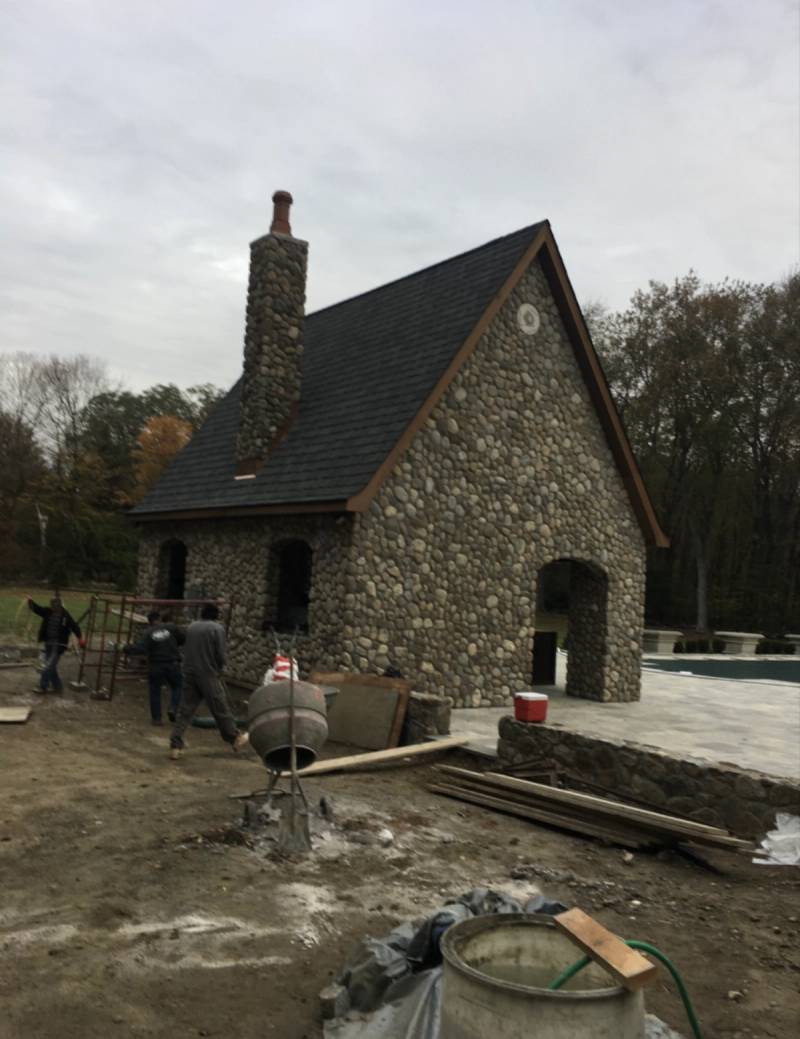 River stone pool house with stone chimney under construction