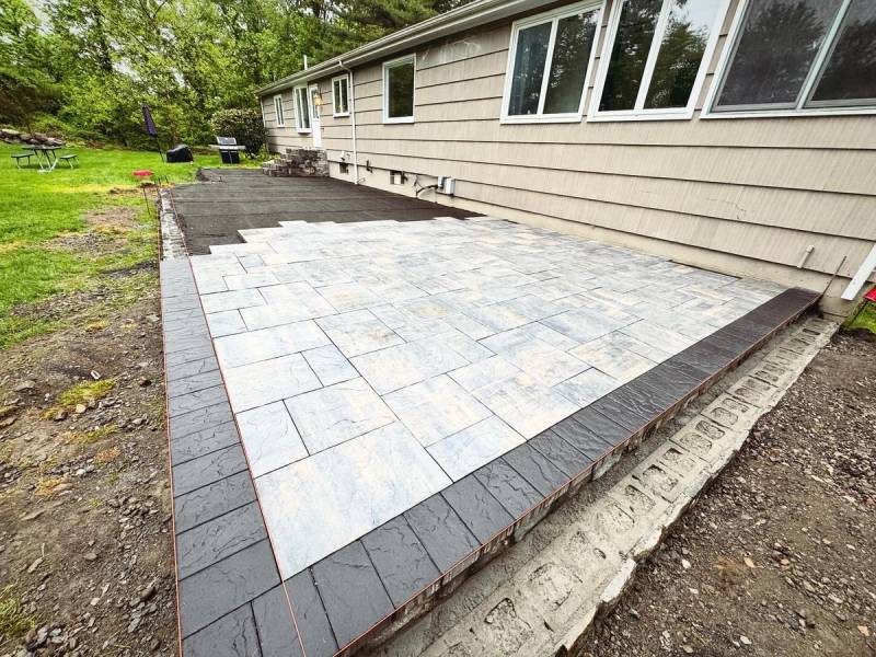 Two-tone paver patio installation with dark border at a residential home