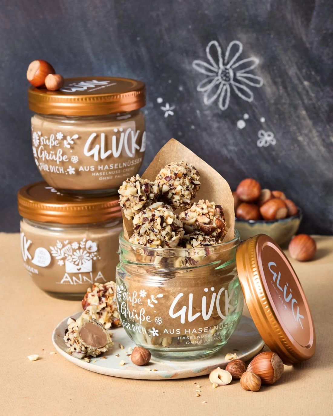 Haselnuss Pralinen zum Verschenken im GLÜCK Glas. Daneben winterliche Dekoration