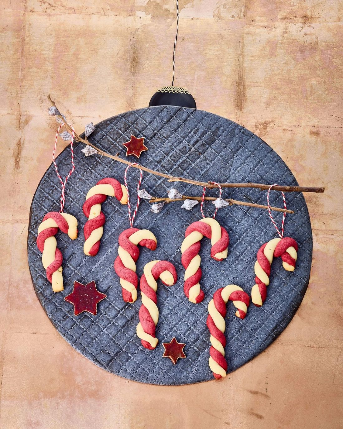 Zuckerstangen-Plätzchen auf einer Unterlage in der Form einer Christbaumkugel.