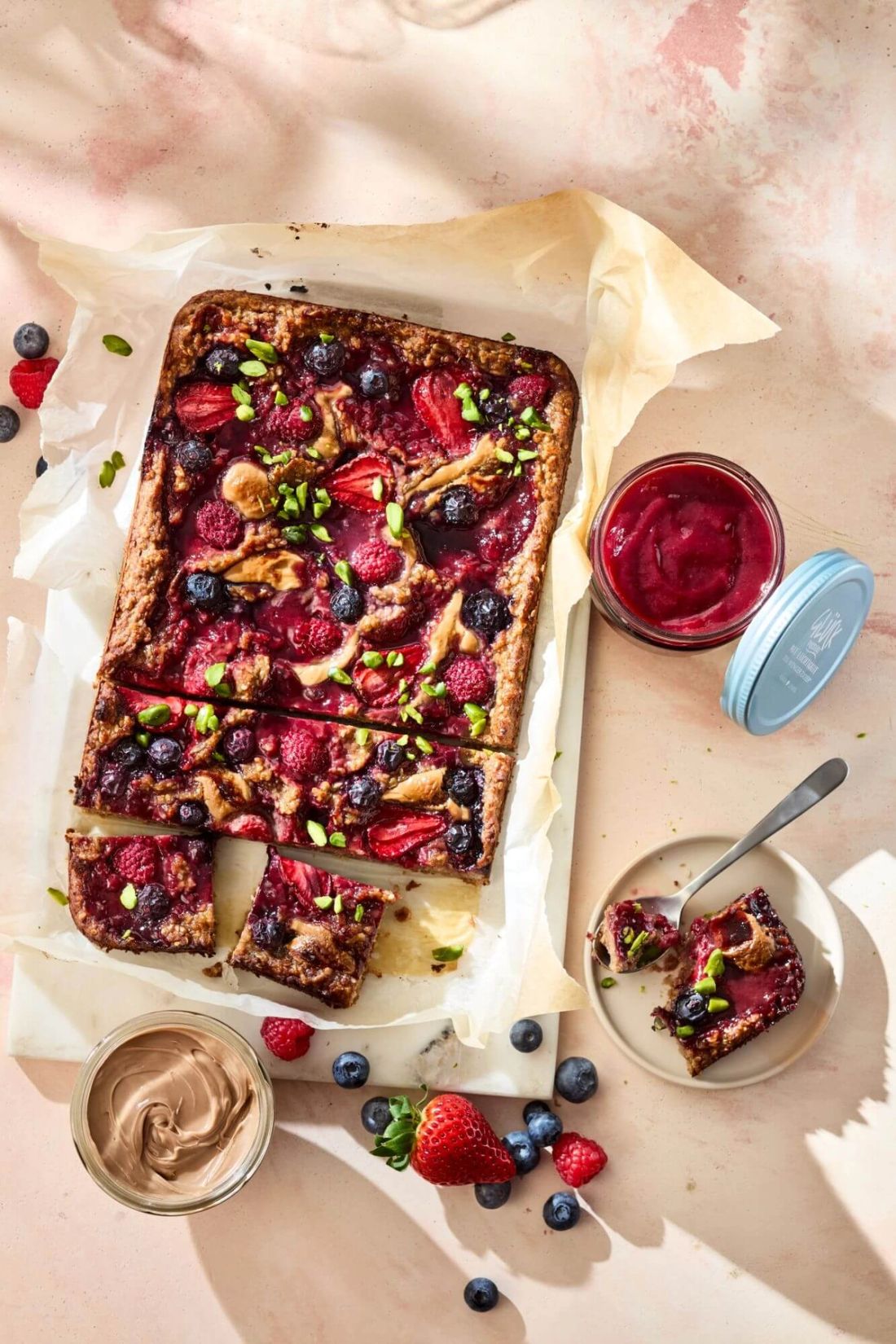 Baked Oats mit Beeren und Pistazien. Daneben ein Glas GLÜCK passiert mit Leichtigkeit aus Kirschen.