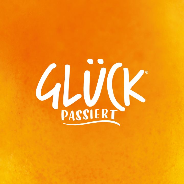 Orangegelber Hintergrund mit leichter Struktur. In der Mitte das Logo "GLÜCK passiert" in weiß mit geschwungener weißer Linie darunter.