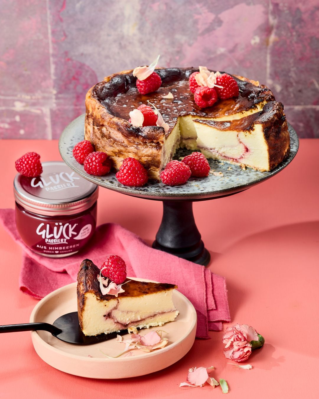Basque-Cheesecake mit Swirl aus GLÜCK passiert aus Himbeeren und garniert mit frischen Himbeeren.