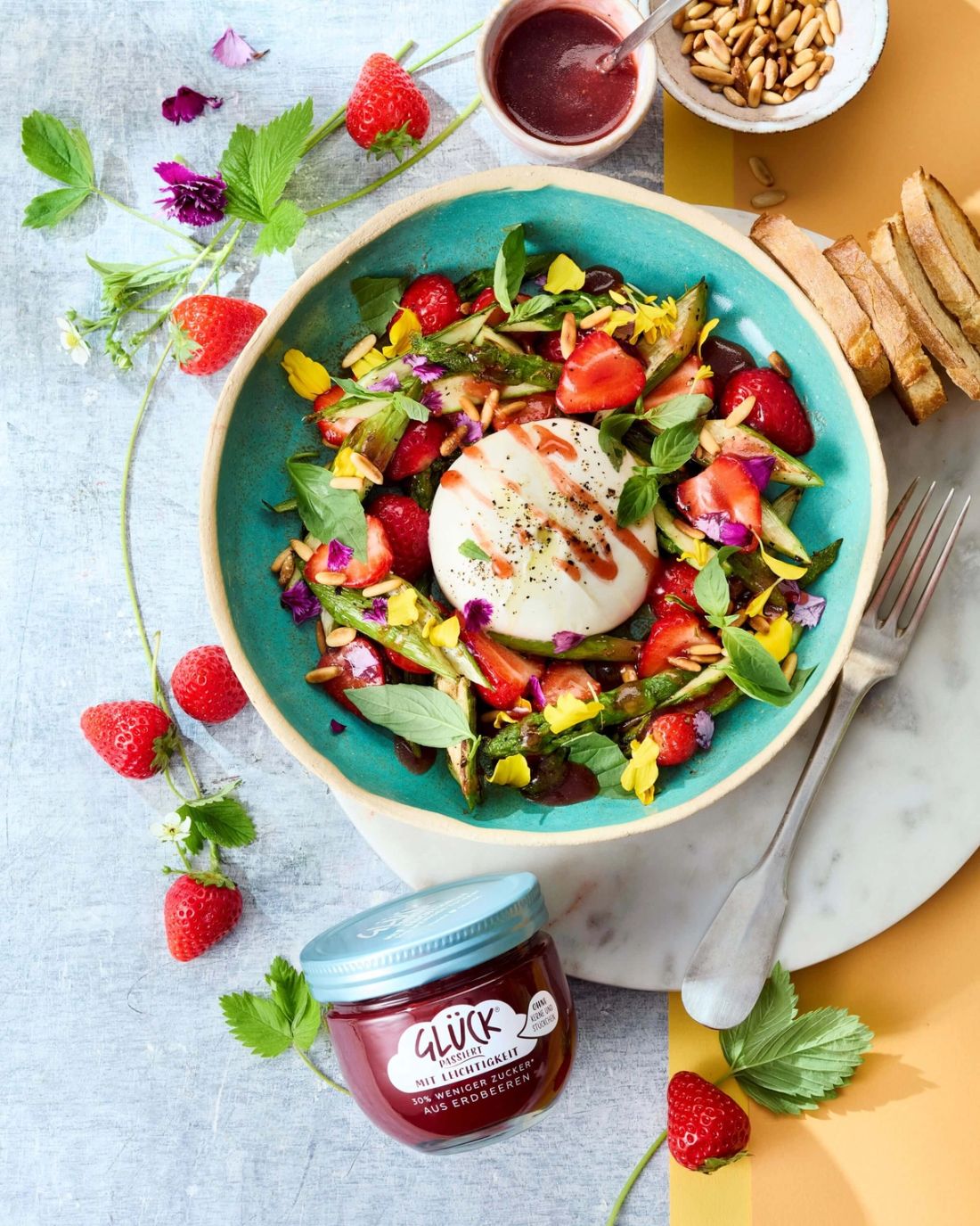 Sommerlicher Salat mit Burrata & Erdbeer-Vinaigrette. Daneben ein Glas GLÜCK passiert mit Leichtigkeit aus Erdbeeren.