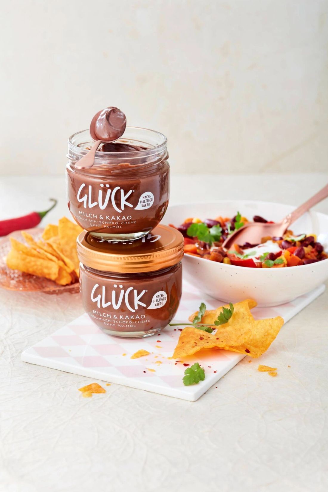Chili sin Carne auf einem Teller. Davor zwei Gläser GLÜCK Milch & Kakao.