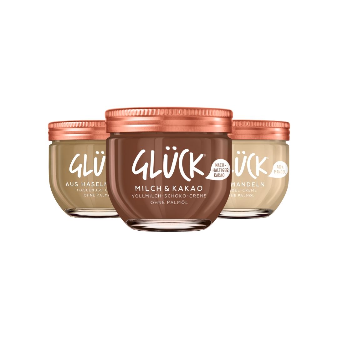 Zu sehen sind die drei Sorten der GLÜCK Schoko- und Nuss-Cremes: GLÜCK Milch & Kakao, GLÜCK aus Mandeln und GLÜCK aus Haselnüssen.
