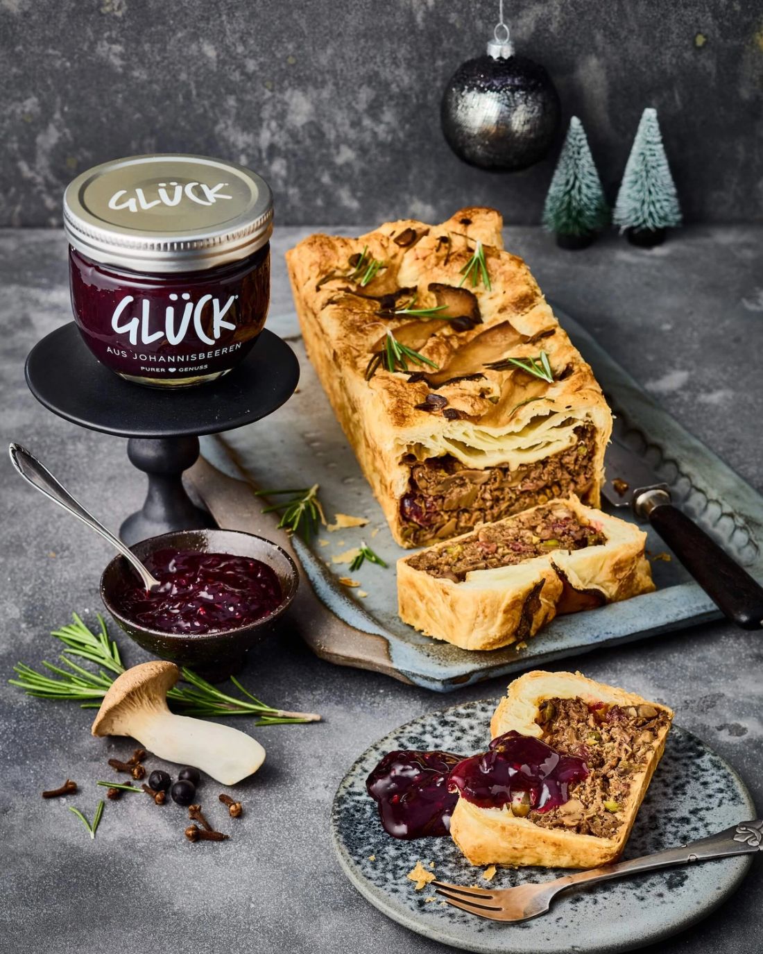 Pilzterrine auf einem Tablett. Daneben ein Glas GLÜCK Marmelade und eine Schale Cumberlandsoße.