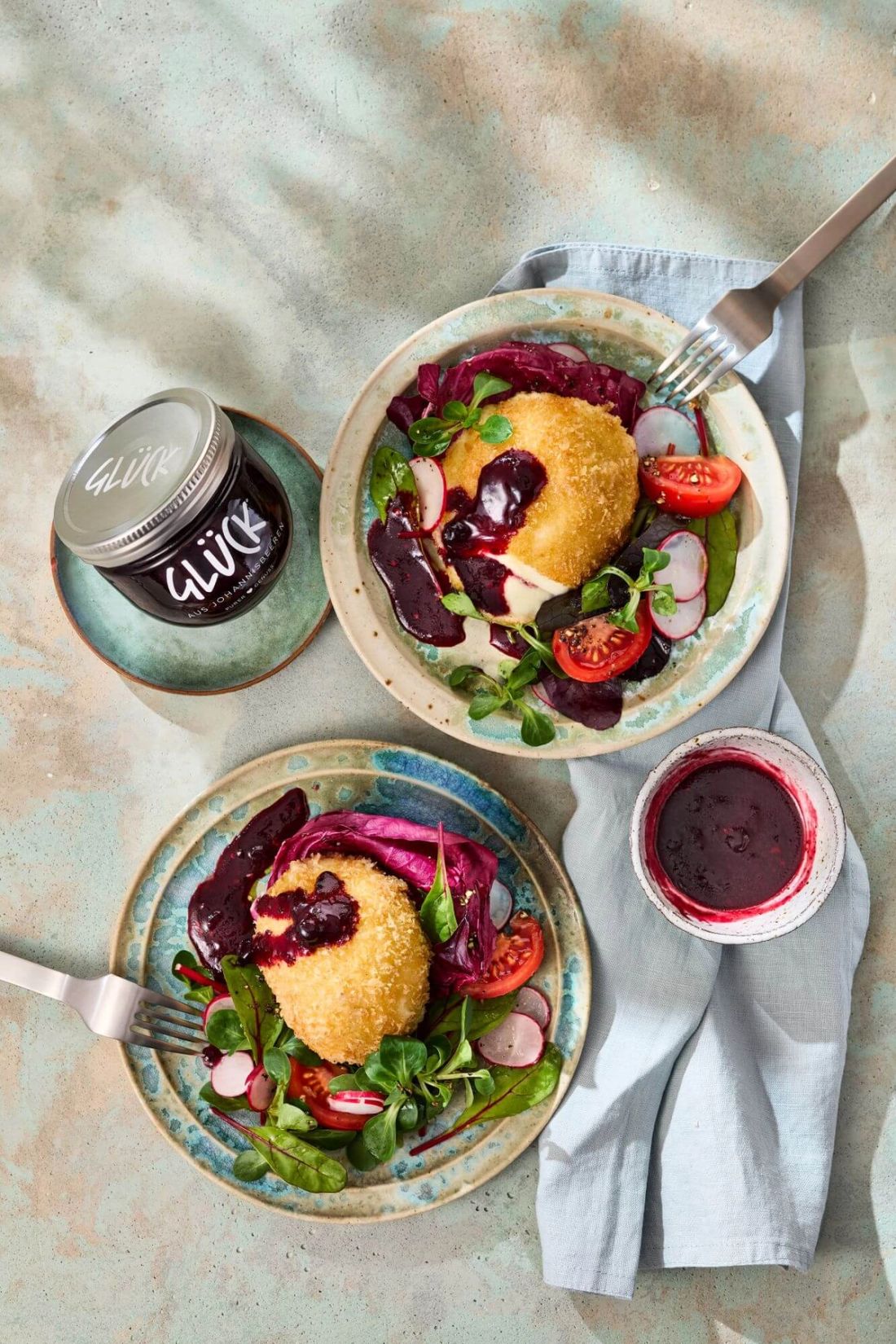 Gebackener Mozzarella mit Johannisbeersoße. Garniert mit Salat und Radieschen. Dabei ein Glas GLÜCK aus Johannisbeeren.