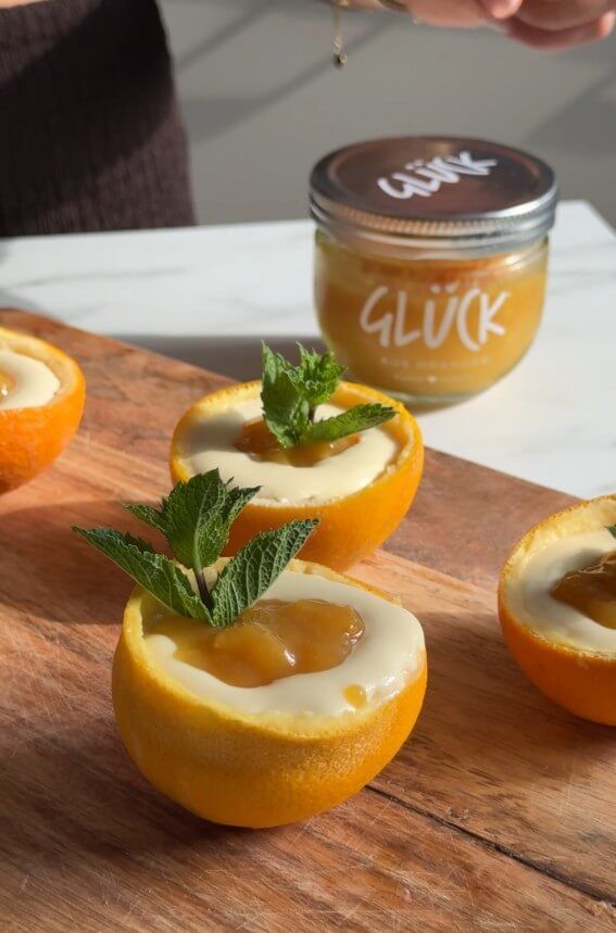 Orangen-Possets angerichtet mit Minze vor einem Glas GLÜCK aus Orangen