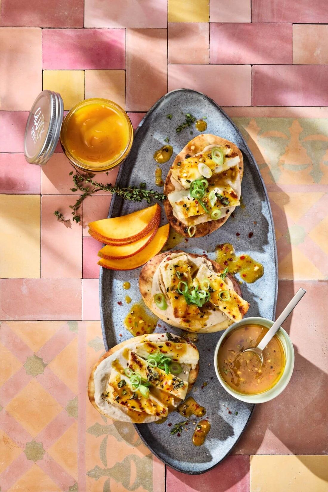 Flatbreads mit Halloumi und Mangosoße. Daneben Garnitur aus Mango und Kräutern.