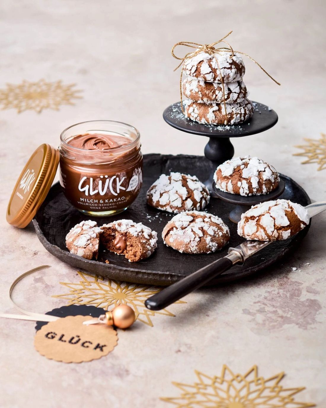 Kakao Crinkle Cookies auf einem Teller. Daneben ein Glas GLÜCK Milch & Kakao.