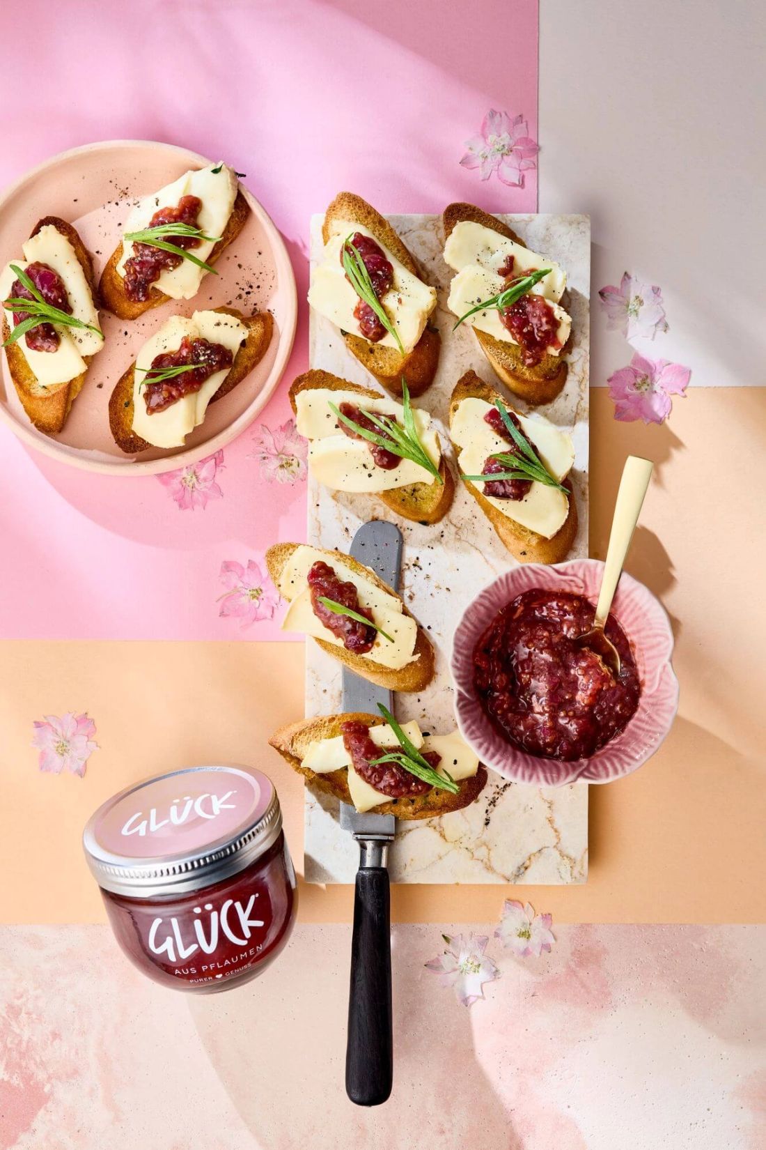 Crostini mit Taleggio und Pflaumensenf. Daneben eine Schale Pflaumensenf und ein Glas GLÜCK aus Pflaumen.