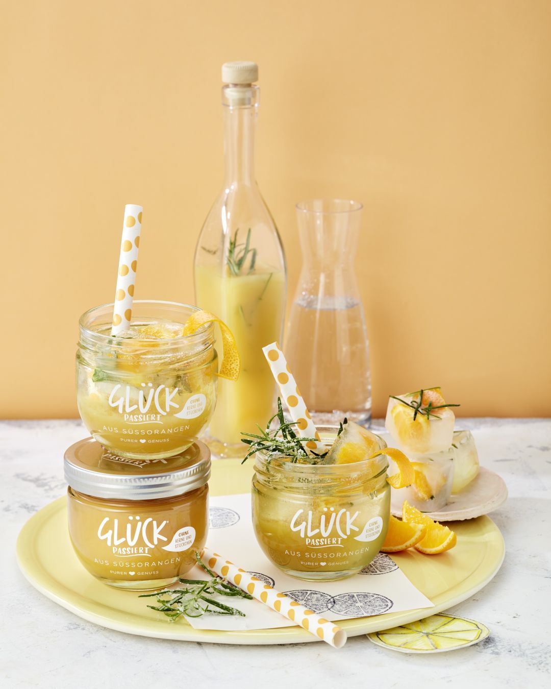 Süßorange-Rosmarin-Sirup im GLÜCK Glas. Daneben ein Glas GLÜCK passiert aus Süßorangen.