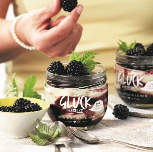 Brombeer Panna Cotta im halbleeren Glas von GLÜCK passiert aus Brombeeren. Garniert mit frischen Brombeeren und Minze.