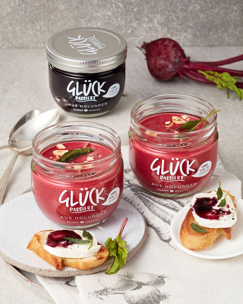 Rote Bete Suppe mit GLÜCK aus Holunder in einem GLÜCK Glas. Daneben Ziegenkäse mit GLÜCK passiert aus Holunder auf Baguettescheiben.